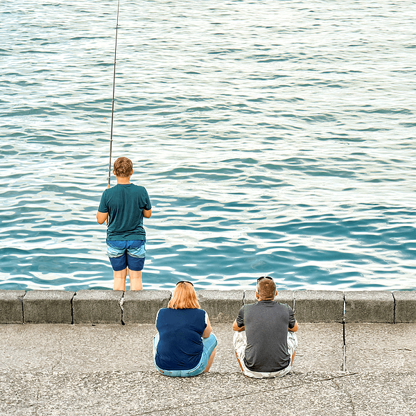 Teen fishing while parents watch from shore