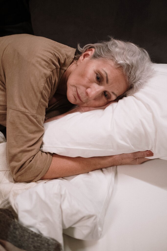 Older woman laying in bed staring off