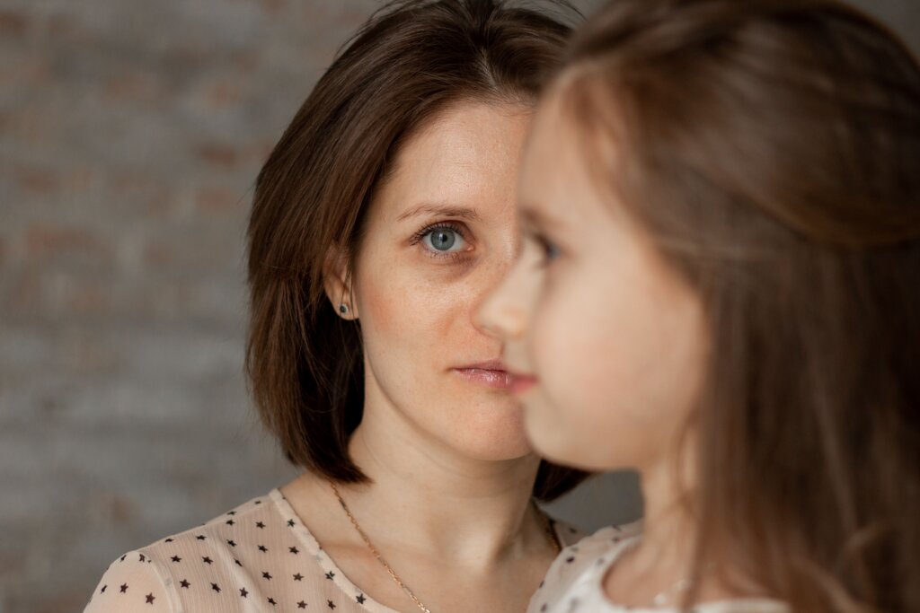 Face of Mom half covered by profile of young daughter