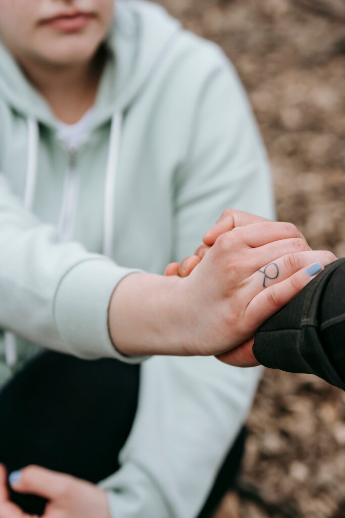 Woman sitting with outstretched hand grasping another person's hand